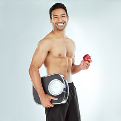 Image showing Scale, health and portrait of fitness man with apple in studio for Weight loss, diet or detox on white background. Nutrition, balance or face of wellness model smile for superfoods, fruit or progress