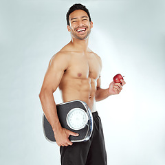 Image showing Health, scale and portrait of fitness man with apple in studio for weight loss, diet or detox on white background. Nutrition, balance or face of wellness model smile for superfoods, fruit or progress