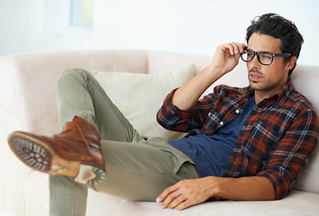 Image showing Home, sofa and man relax with glasses for eyesight and headache from problem with vision in living room. Hipster, person and thinking on couch in apartment with spectacles for farsighted healthcare