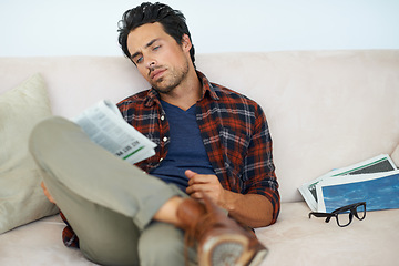 Image showing Man, reading and relax with newspaper on couch in home, living room and learning about event from media. Calm, weekend and person with news, paper or magazine on sofa in apartment for information