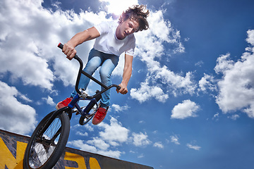 Image showing Bike, jump and teen on ramp for sport performance, ride or training for event at park with sky. Bicycle, stunt or kid balance on edge of board for cycling trick in competition or challenge with risk