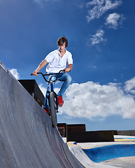 Image showing Riding, bike and teen on ramp for sport performance, jump or training for event at skatepark with sky mockup. Bicycle, stunt or kid balance on edge of board in trick for cycling competition challenge