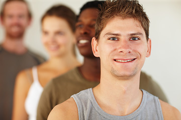 Image showing Portrait, smile or fitness and man with a group of people in a studio for health, wellness or mindfulness. Exercise, workout and pilates with a happy young person in gym class for holistic training