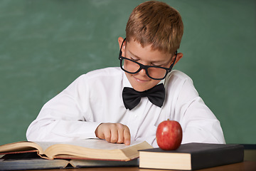 Image showing Young boy, book and reading at school for learning, education or knowledge by green chalk board. Male person, smart child or teenager smile with textbook for academic literature or studying in class