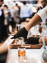 Image showing Expert barman is making cocktail at business banquet event in hotel conference center. Blurred businesspeople at banquet event business meeting event in the background