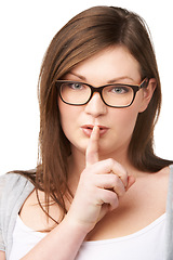 Image showing Studio portrait and plus size model with secret for hush, gossip and privacy news with mystery by white background. Woman, face and emoji for shush with glasses, confidential and silence for noise