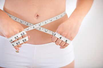 Image showing Hands, body and woman with tape measure on abdomen in underwear for weight loss, health and wellness isolated on a white studio background. Closeup, stomach and girl measuring waist for diet or care