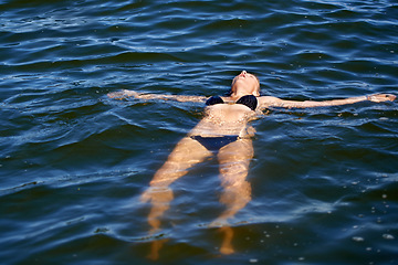 Image showing Ocean, water and woman floating in bikini with peace and freedom in summer, holiday or vacation. Person, relax and calm swimming in sea, lake or pool with swimwear, costume and waves offshore