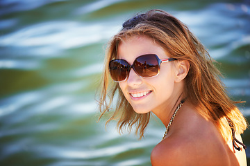 Image showing Lake, portrait or happy woman in nature to relax with sunglasses, freedom or adventure in summer. Smile, paradise or female person in river water or dam for holiday travel, peace or outdoor vacation
