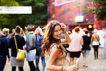 Image showing Music, festival and portrait of woman at a concert, field with crowd and audience or excited fan at event. Happy, girl and walking to stage or dancing with drink at party with alcohol and celebration