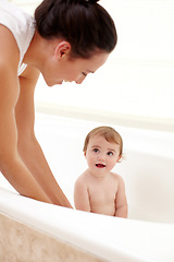 Image showing Baby in bathtub with mom, water and clean fun in home for skincare, wellness and hygiene. Bubble bath, soap and happy child in bathroom with cute face, care and washing body of dirt, germs and mother