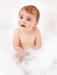 Image showing Baby in bathtub with foam, water and clean fun in home for skincare, wellness and hygiene. Bubble bath, soap and happy child in bathroom with cute face, care and washing body of dirt, germs and smile