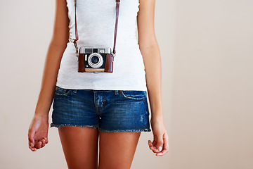 Image showing Camera, woman and closeup of a photographer in studio for travel, photography or creativity. Trendy casual fashion of a female model person, student or tourist on a white background in shorts