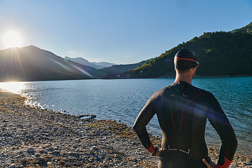 Image showing Authentic triathlon athlete getting ready for swimming training on lake