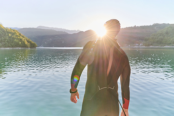 Image showing Authentic triathlon athlete getting ready for swimming training on lake