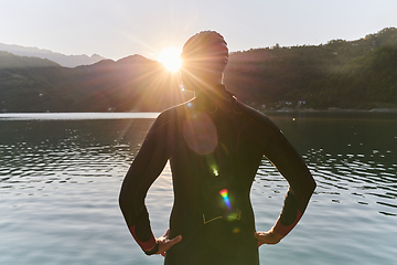 Image showing Authentic triathlon athlete getting ready for swimming training on lake