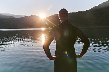 Image showing Authentic triathlon athlete getting ready for swimming training on lake