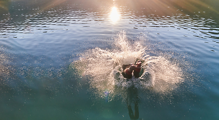 Image showing Triathlon athlete swimming on lake in sunrise wearing wetsuit