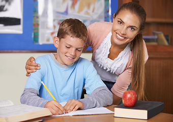 Image showing Happy teacher, student and care in support for education, learning or tutor in classroom at school. Portrait of woman, mentor or teaching boy in writing, literature or test for exam or help in class