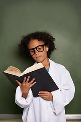 Image showing Child, classroom and reading book for education, science learning and physics knowledge on a chalkboard background. Kid or young student with glasses for library resources, textbook and school