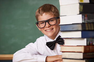 Image showing Boy student, smile and portrait with books, classroom and learning for exam, assessment and studying for knowledge. Child, notebook and happy for education, development and glasses by chalkboard