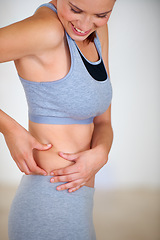 Image showing Fitness, stomach and woman holding skin for health, wellness and weight loss goals in a training studio. Smile, happy and young female person athlete showing body for exercise or workout at gym.