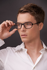 Image showing Man, thinking and serious nerd with glasses, fashion or choice in eyewear on dark background of studio. Optometry, check and geek with spectacles, style and person with prescription lenses in frame