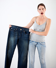 Image showing Diet, weight loss and woman with surprise from jeans, change in size or white background in studio. Shocked, portrait or person with crazy reaction to transformation in fitness or large denim pants