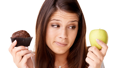 Image showing Face, choice and apple or muffin with a woman in studio isolated on a white background for food decision. Doubt, health or nutrition with a confused young person holding fruit and dessert options