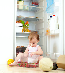 Image showing Toddler, little girl and fruit from fridge in kitchen for eating, hunger or curiosity of container. Youth, child and busy with organic, fresh and snack with strawberry with development of motor skill