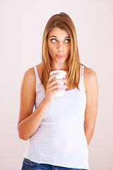 Image showing Woman, drink and studio with cup of soda, fizzy cola and ice cold milkshake isolated on white background. Thirsty young girl, thinking and sip straw for takeaway beverage, juice or fast food smoothie