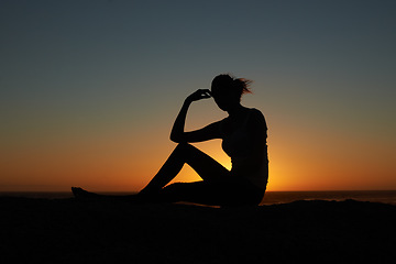 Image showing Sunset, silhouette and woman at a beach relax, resting and enjoying quiet morning on sky background. Sunrise, shadow and female person at the ocean for travel, freedom and peaceful me time in nature