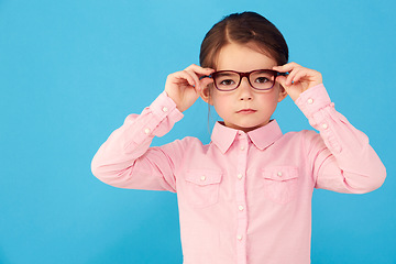 Image showing Glasses, child and portrait with eye, geek and modern fashion in a studio with serious face. Kid, eyewear and sight with youth outfit and nerd with accessory and blue background with confidence