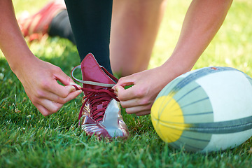 Image showing Rugby, ball and sports with shoes of person on field for training, practice and challenge. Health, start and games with closeup of athlete tying laces on outdoor pitch for stadium and fitness