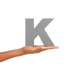 Image showing Hand of woman, capital letter K and presentation of consonant isolated on white background. Character, font and palm with English alphabet typeface for communication, reading and writing in studio.