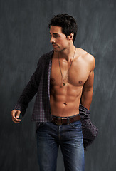 Image showing Handsome, fashion and young man by a wall with trendy, cool and stylish outfit with confidence. Abs, attractive and male model from Canada with casual shirt and jeans posing by gray background.