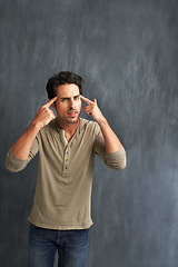 Image showing Annoyed, thinking and portrait of man by a wall with doubt, moody and angry facial expression. Upset, question and young male person from Canada with confused face pointing to head by gray background