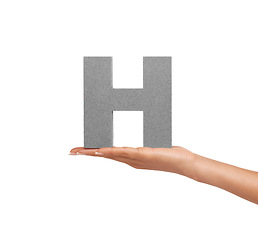 Image showing Hand of woman, capital letter H and presentation of consonant isolated on white background. Character, font and palm showing English alphabet typeface for communication, reading and writing in studio