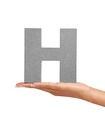 Image showing Hand of woman, font letter H and presentation of consonant isolated on white background. Character, uppercase and palm with English alphabet typeface for communication, reading and writing in studio.