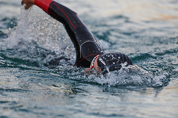 Image showing A professional triathlete trains with unwavering dedication for an upcoming competition at a lake, emanating a sense of athleticism and profound commitment to excellence.