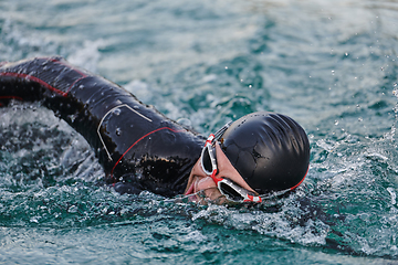 Image showing A professional triathlete trains with unwavering dedication for an upcoming competition at a lake, emanating a sense of athleticism and profound commitment to excellence.