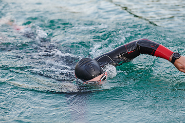 Image showing A professional triathlete trains with unwavering dedication for an upcoming competition at a lake, emanating a sense of athleticism and profound commitment to excellence.