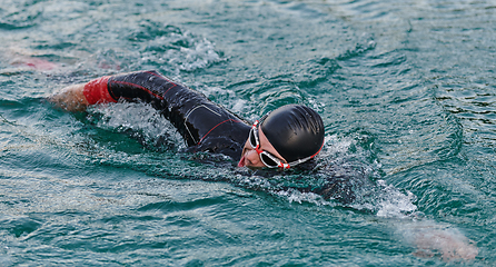 Image showing A professional triathlete trains with unwavering dedication for an upcoming competition at a lake, emanating a sense of athleticism and profound commitment to excellence.