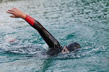 Image showing A professional triathlete trains with unwavering dedication for an upcoming competition at a lake, emanating a sense of athleticism and profound commitment to excellence.