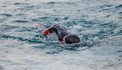 Image showing A professional triathlete trains with unwavering dedication for an upcoming competition at a lake, emanating a sense of athleticism and profound commitment to excellence.