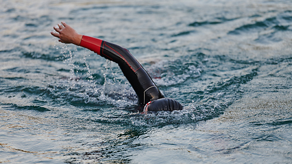 Image showing A professional triathlete trains with unwavering dedication for an upcoming competition at a lake, emanating a sense of athleticism and profound commitment to excellence.