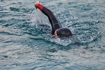 Image showing A professional triathlete trains with unwavering dedication for an upcoming competition at a lake, emanating a sense of athleticism and profound commitment to excellence.