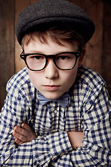 Image showing Portrait, glasses and serious kid with arms crossed for fashion, retro or vintage. Confident face, nerd and young boy child in hat, geek in stylish eyewear and trendy casual clothes in New Zealand