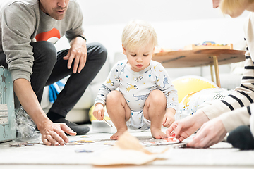 Image showing Parents playing games with child. Little toddler doing puzzle. Infant baby boy learns to solve problems and develops cognitive skills. Child development concept