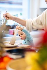 Image showing Mother and little toddler baby boy making pancakes for breakfast together in domestic kitchen. Family, lifestyle, domestic life, food, healthy eating and people concept.